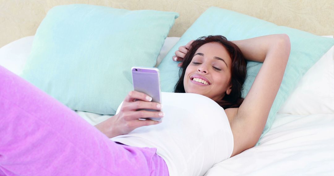 Smiling Young Woman Relaxing in Bed Using Smartphone - Free Images, Stock Photos and Pictures on Pikwizard.com