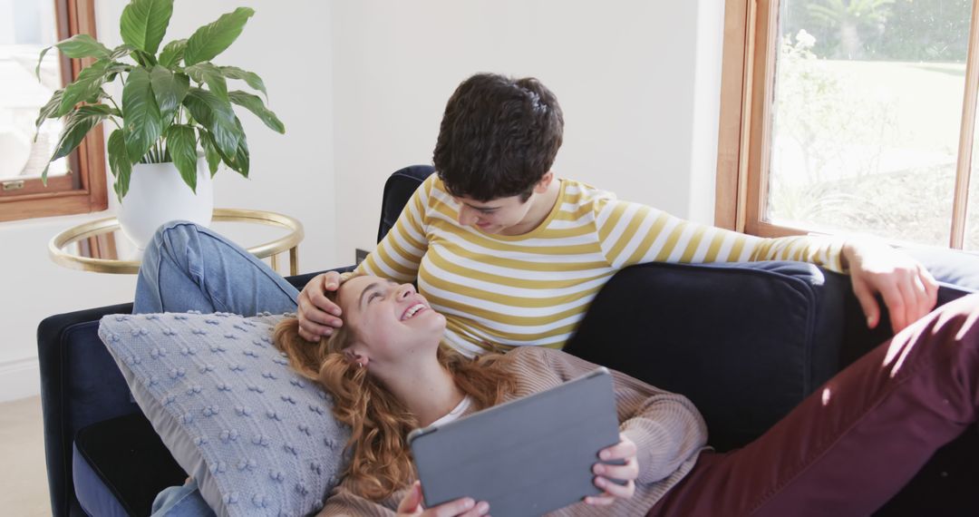Happy Lesbian Couple Relaxing on Sofa with Tablet