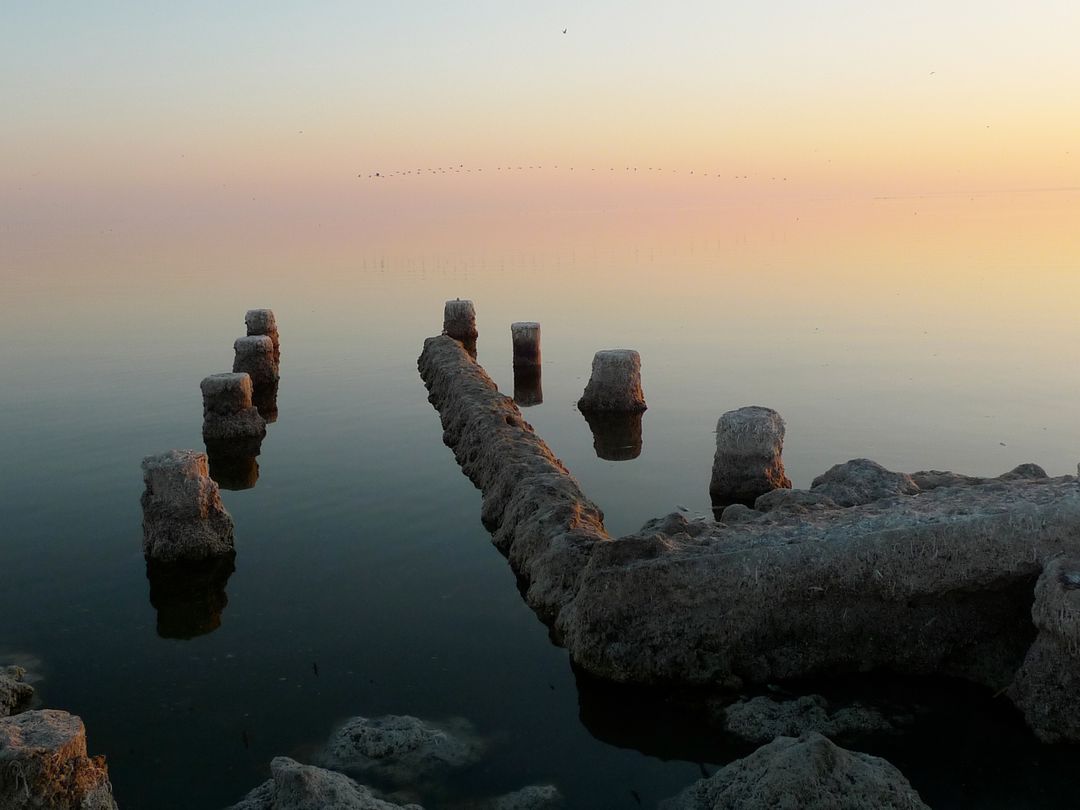 Calm Sunset Water Scene with Remnants of Wooden Piers - Free Images, Stock Photos and Pictures on Pikwizard.com