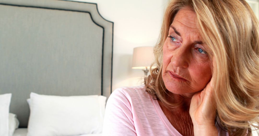 Senior Woman Sitting on Bed Looking Thoughtful - Free Images, Stock Photos and Pictures on Pikwizard.com