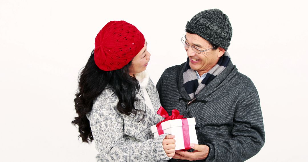 Happy Couple Exchanging Gift Wearing Winter Attire - Free Images, Stock Photos and Pictures on Pikwizard.com