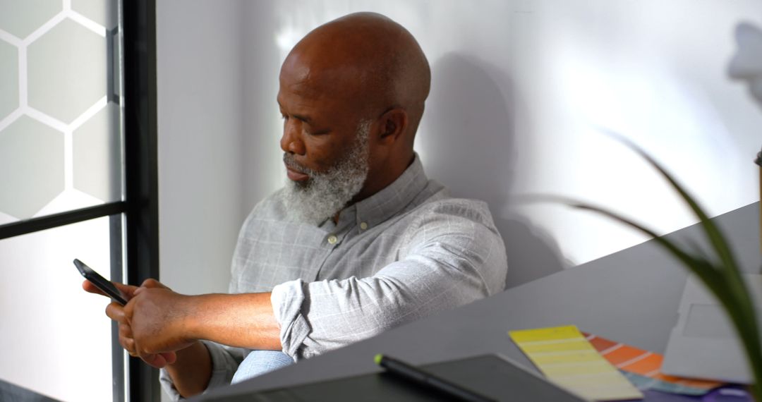 Senior African American Man Sitting at Home Using Smartphone - Free Images, Stock Photos and Pictures on Pikwizard.com