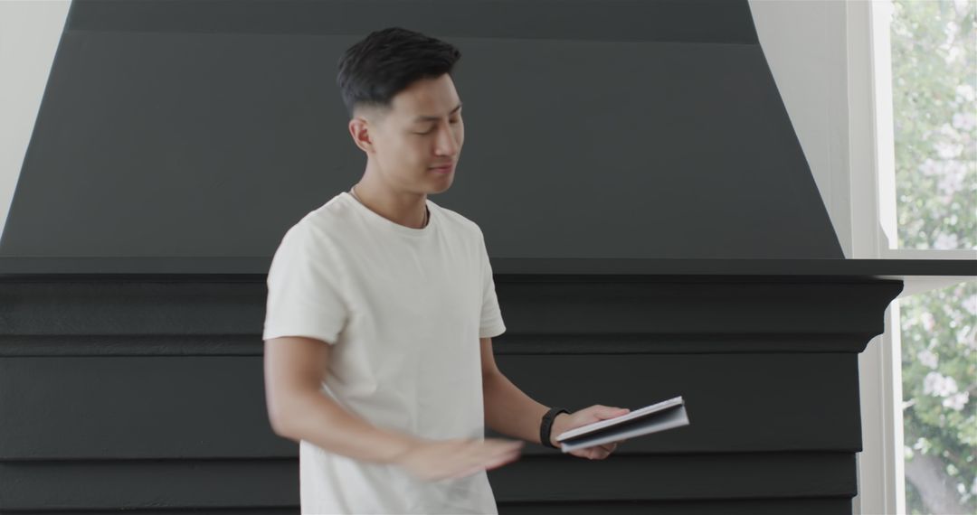 Young Man Holding Notebook Indoors by Fireplace in Casual Style