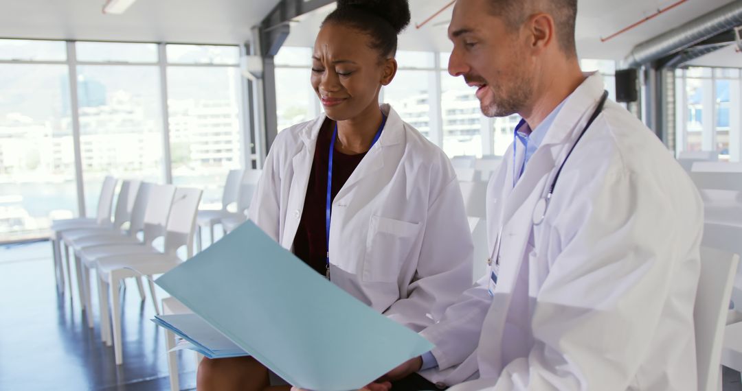 Two Doctors Discussing Medical Files in Bright Hospital Room - Free Images, Stock Photos and Pictures on Pikwizard.com