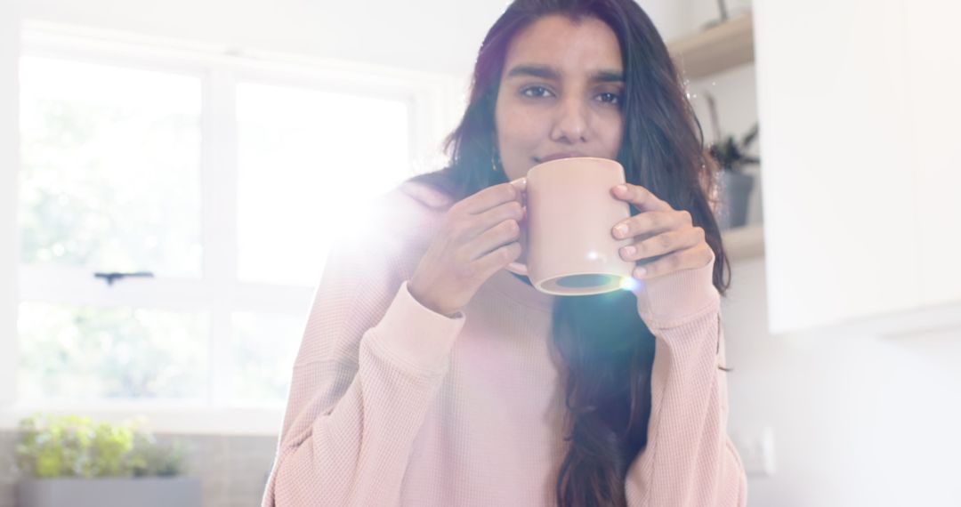 Young Woman Enjoying Morning Coffee in Sunlit Kitchen
