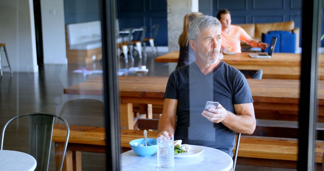 Mature Man Using Phone in Modern Cafeteria - Free Images, Stock Photos and Pictures on Pikwizard.com