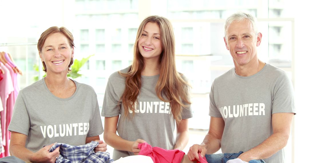 Volunteers Sorting Clothing Smiling in Community Donation Center - Free Images, Stock Photos and Pictures on Pikwizard.com