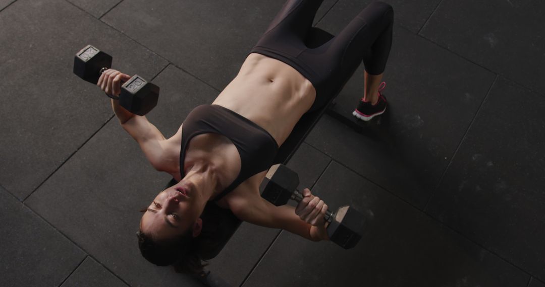 High Angle View of Woman Lifting Dumbbells in Gym