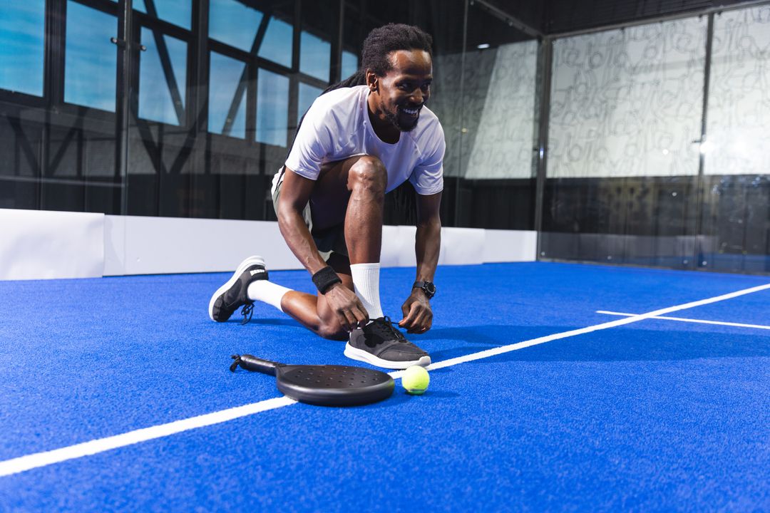 Athlete Tying Laces on Padel Court with Racket and Ball
