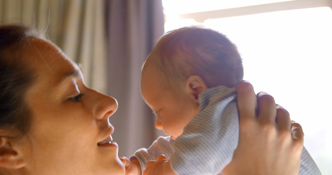 Mother Holding Newborn Baby by Sunlit Window - Free Images, Stock Photos and Pictures on Pikwizard.com