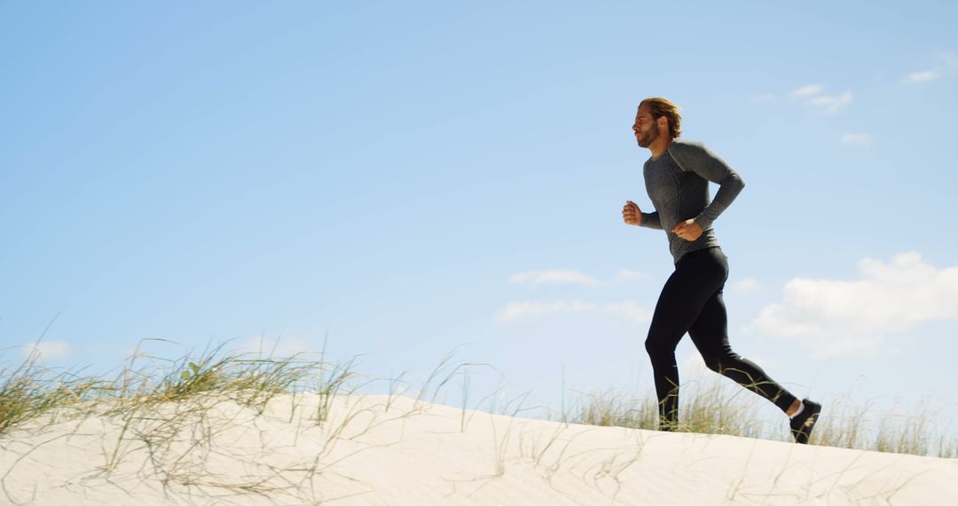 Man Running on Sandy Beach Under Blue Sky, Wearing Athletic Wear - Free Images, Stock Photos and Pictures on Pikwizard.com