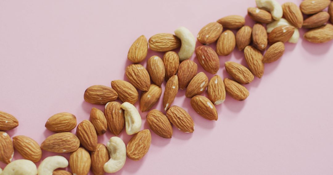 Almonds and Cashews on Pink Background for Vegan Healthy Eating Concept