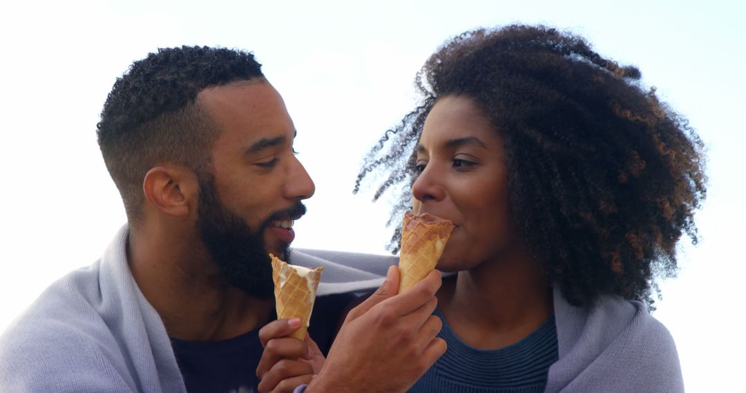 Romantic diverse couple with blankets on backs eating ice creams, copy space - Free Images, Stock Photos and Pictures on Pikwizard.com