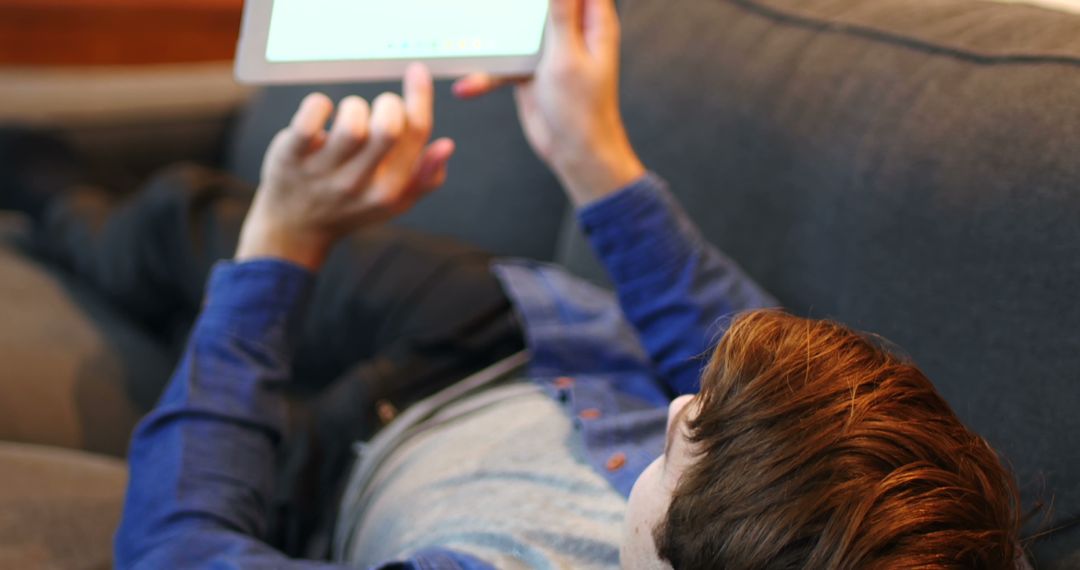 Young Man Relaxing on Sofa Using Tablet Device - Free Images, Stock Photos and Pictures on Pikwizard.com