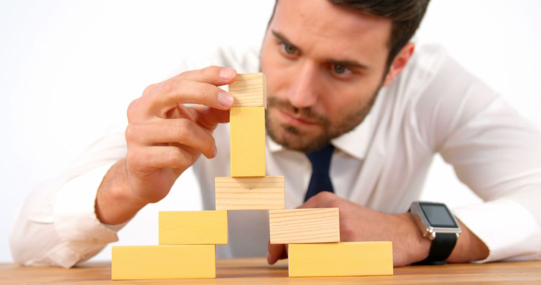 Focused Businessman Building Tower with Wooden Blocks - Free Images, Stock Photos and Pictures on Pikwizard.com