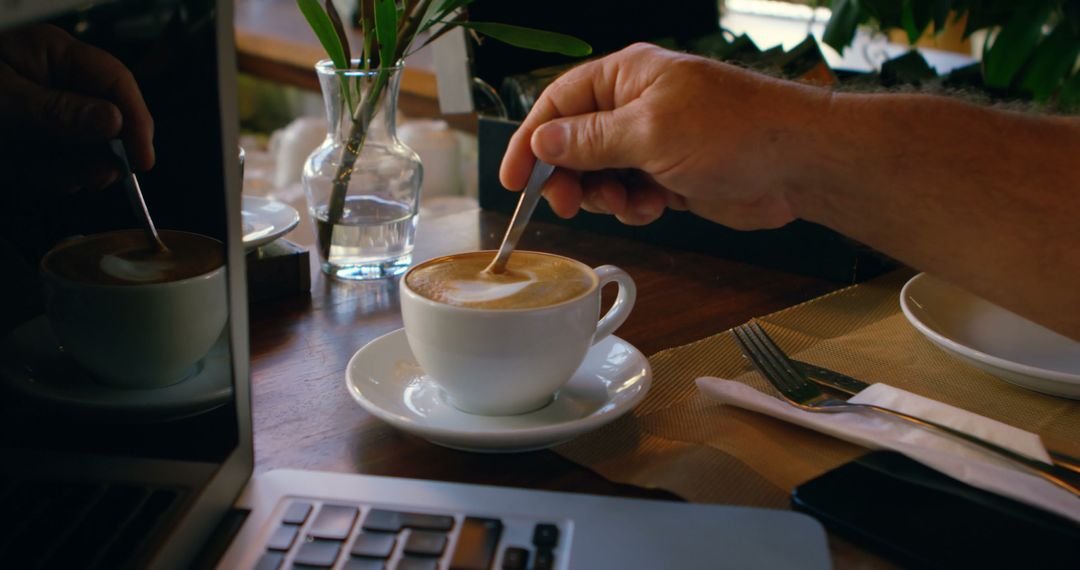 Person Stirring Latte Near Laptop and Table Setting in Cafe - Free Images, Stock Photos and Pictures on Pikwizard.com