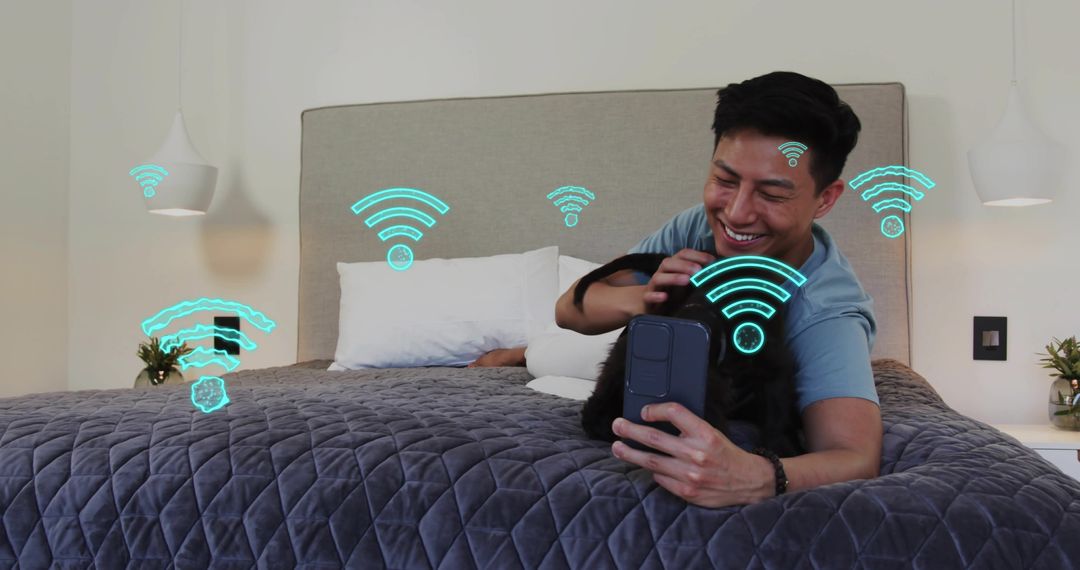 Smiling man petting black dog on bed using smartphone with WiFi icons for smart living