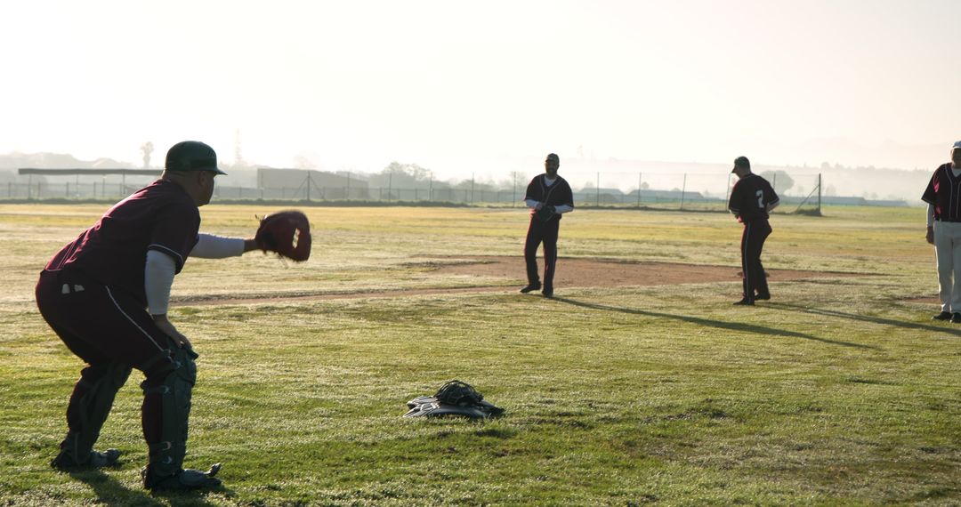 Baseball Team Practicing Fielding on Grassy Field at Sunrise