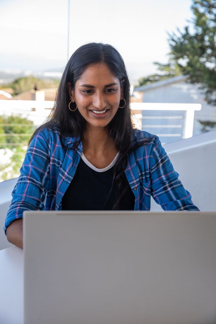 Smiling Woman Using Laptop on Balcony in Casual Setting