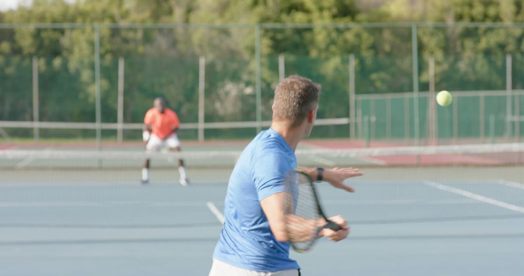 Men Enjoying Competitive Tennis Match Outdoors on Sunny Day - Free Images, Stock Photos and Pictures on Pikwizard.com