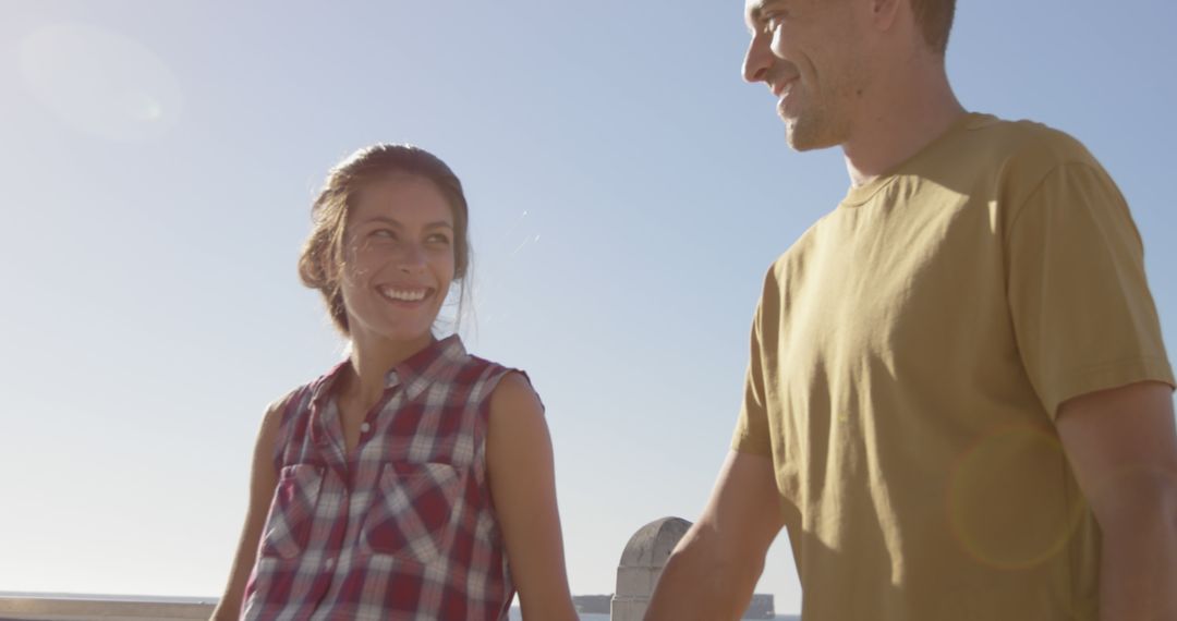 Happy Couple Walking on Beachside Walkway Smiling at Each Other