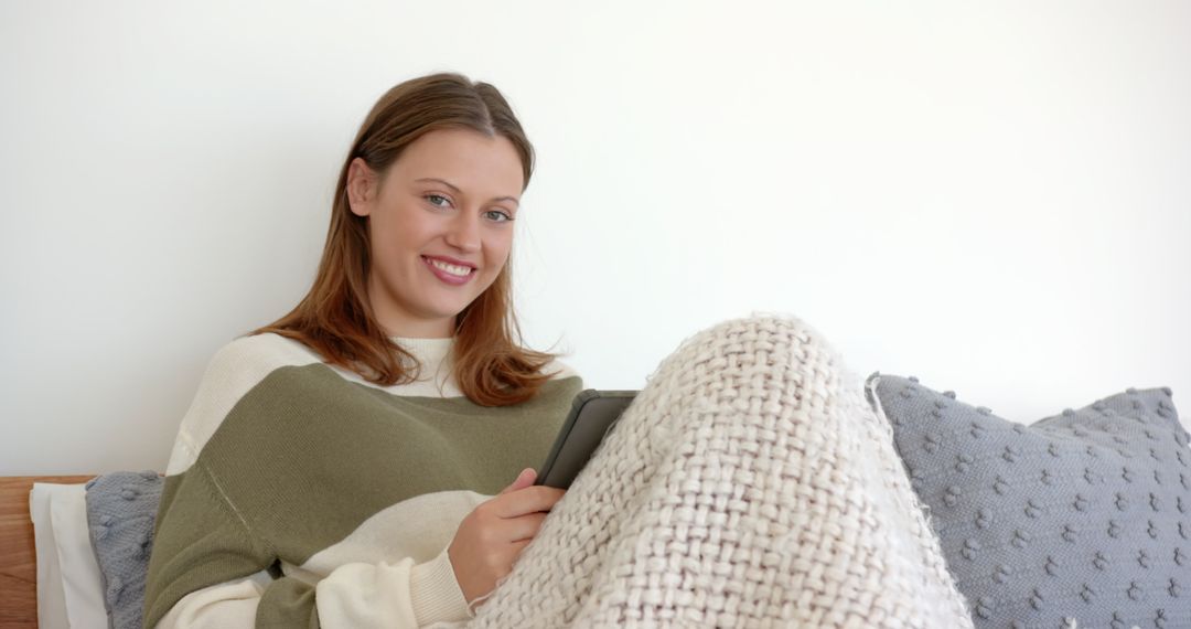 Smiling Woman Relaxing with Tablet and Chunky Knit Blanket