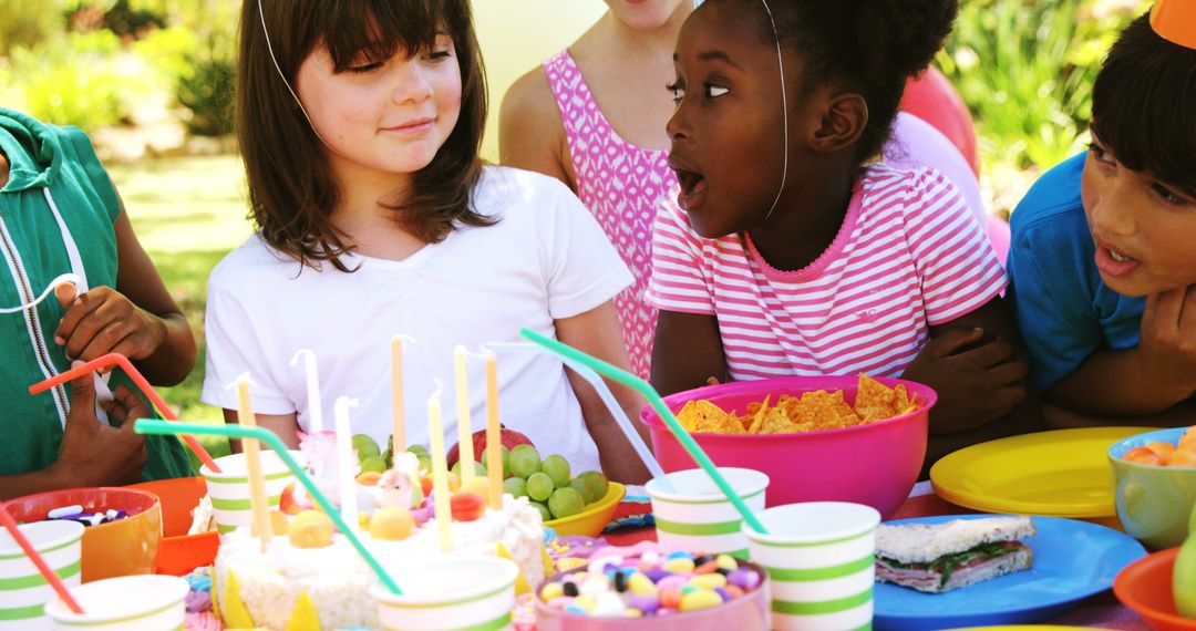 Children radiate joy at an outdoor birthday party, surrounded by snacks and cake. - Free Images, Stock Photos and Pictures on Pikwizard.com