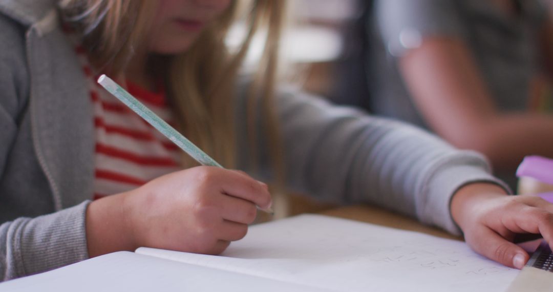 Young Student Writing in Notebook at School Desk