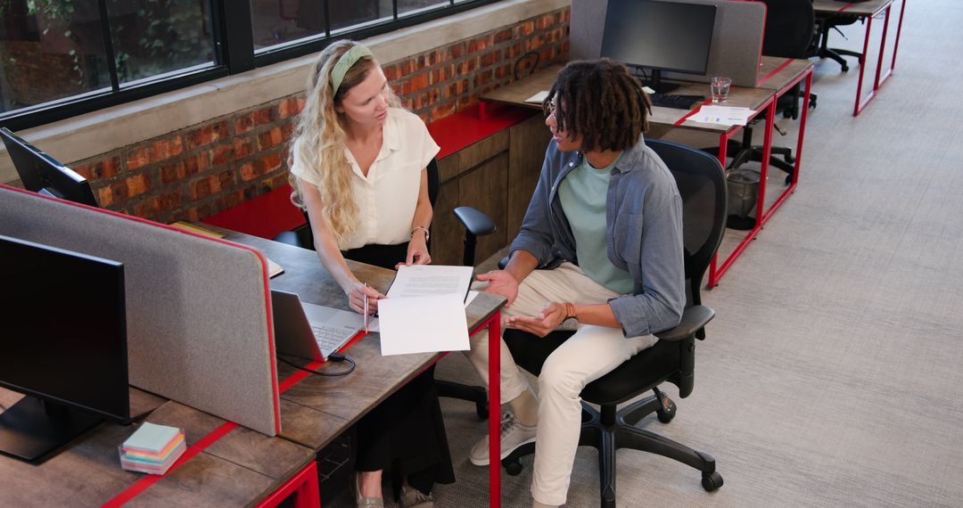 Colleagues Collaborating at Office Desk on Project Proposal