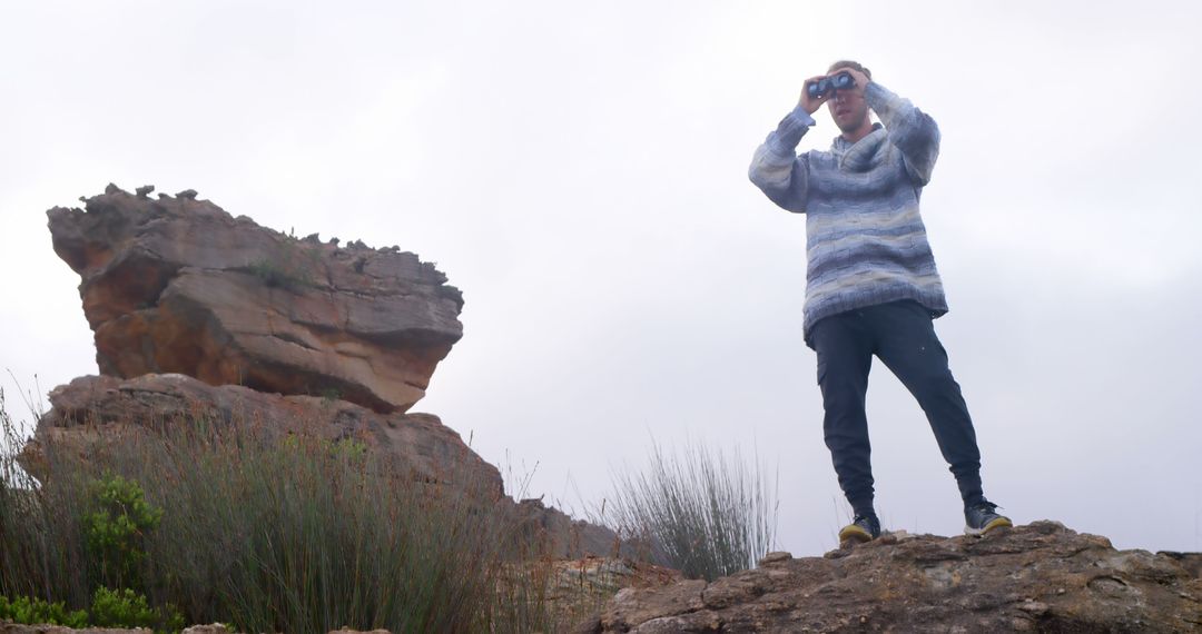 Man Scanning Horizon with Binoculars in Rocky Landscape - Free Images, Stock Photos and Pictures on Pikwizard.com