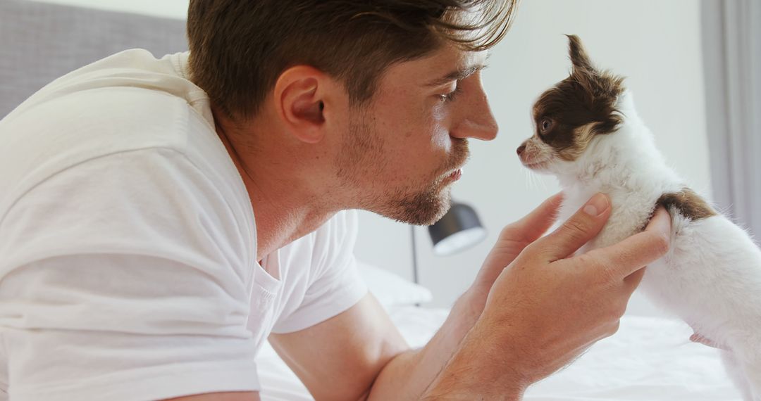 Man Connecting Deeply with Small Puppy on Bed