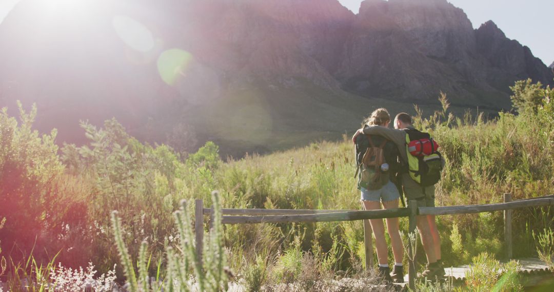 Couple Hiking in Mountain Terrain with Backpacks and Sunflare - Free Images, Stock Photos and Pictures on Pikwizard.com