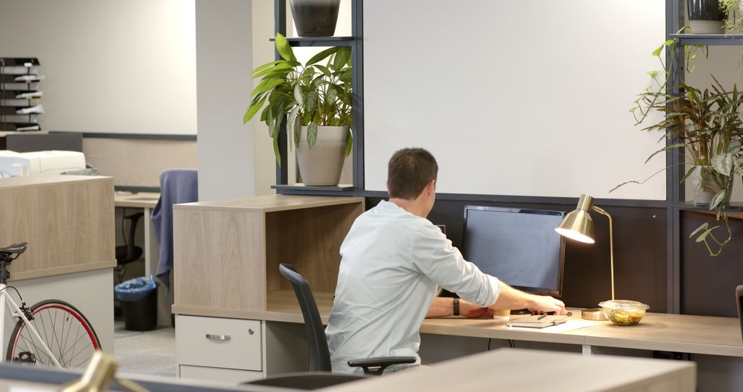 Man Working in Modern Open-Plan Office with Greenery and Snacks
