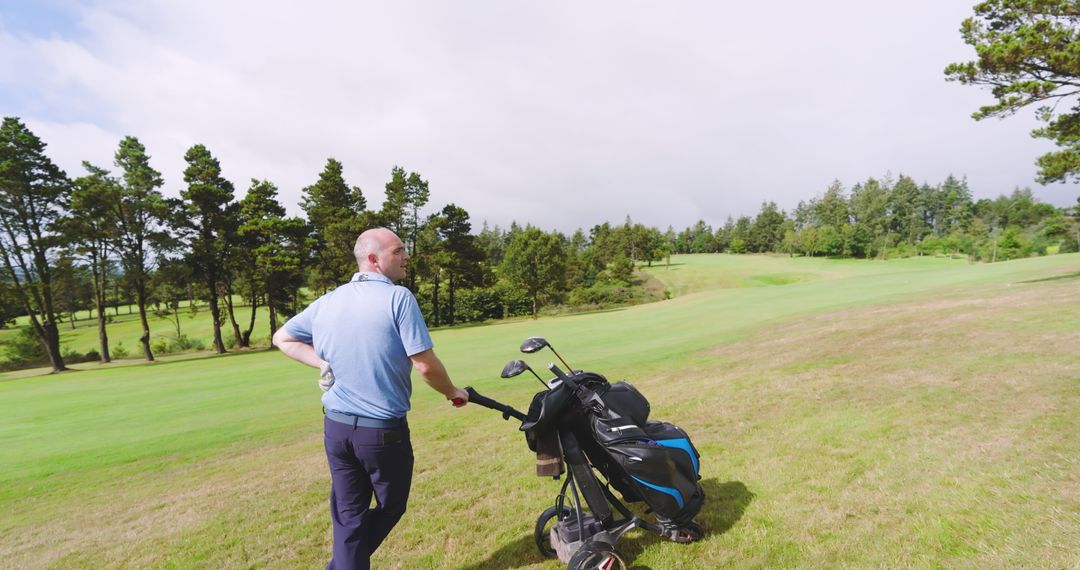 Golfer Enjoying Day on Lush Golf Course with Trolley and Clubs