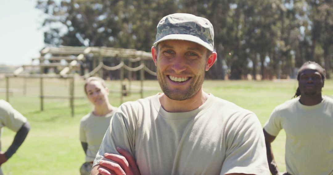 Smiling Soldier at Obstacle Course with Team Behind Him