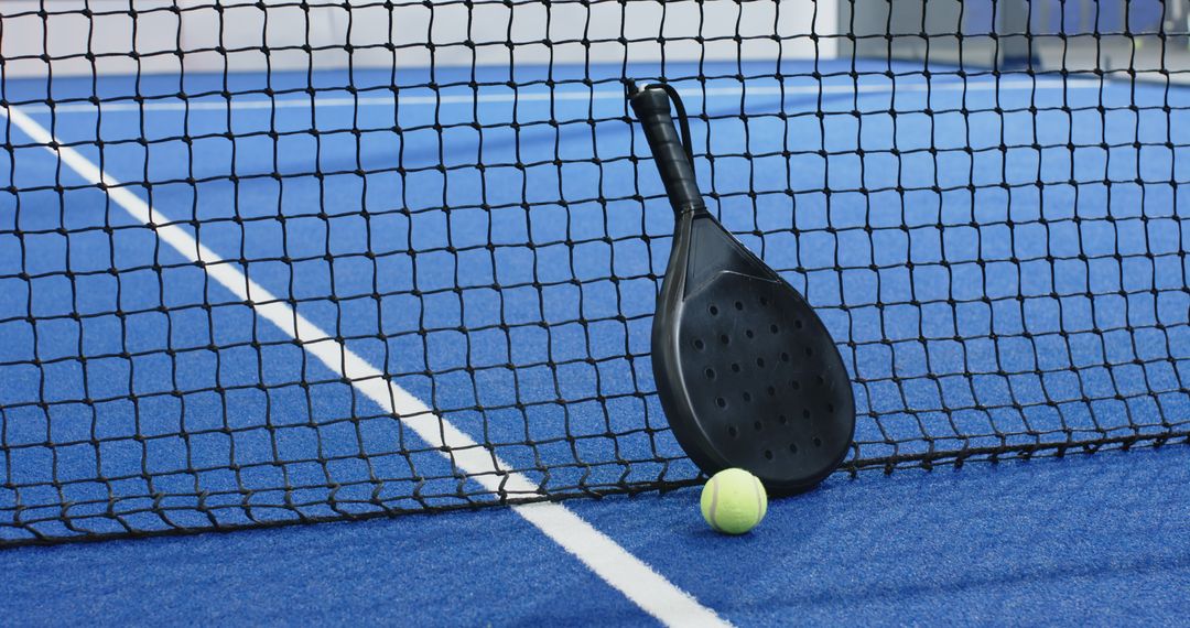 Black Padel Racket with Ball on Blue Turf Court