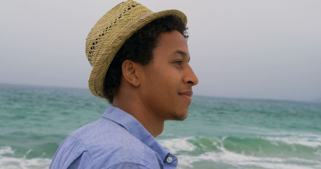 Joyful Man Wearing Hat Looking at Ocean Waves on Beach