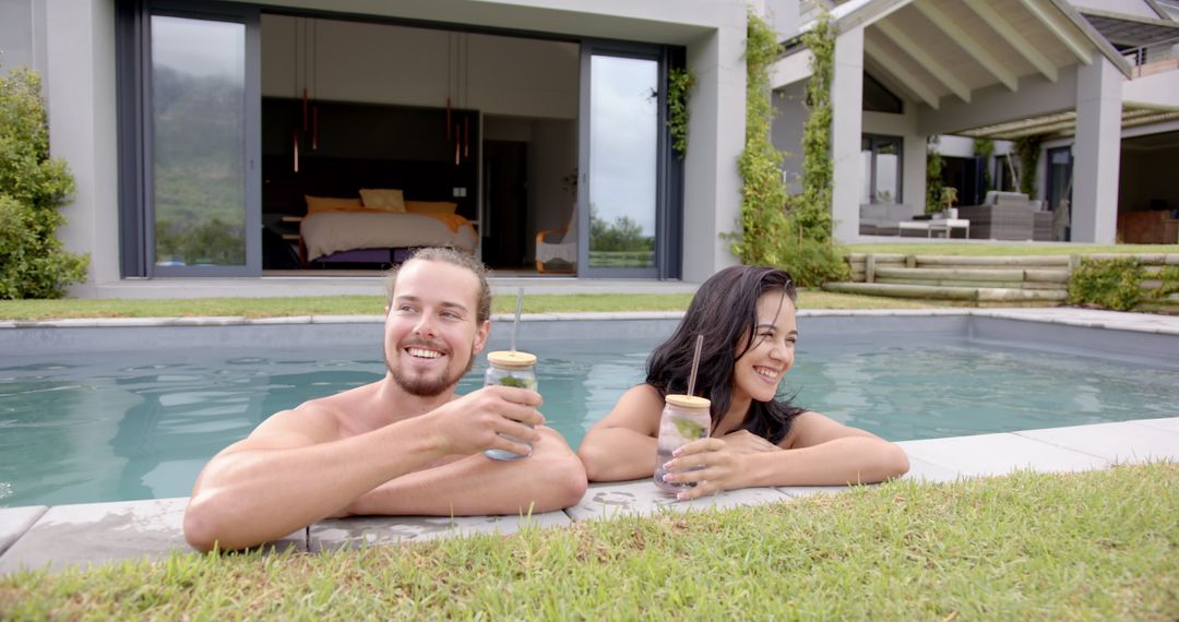 Young Diverse Couple Relaxing with Drinks by Modern Poolside