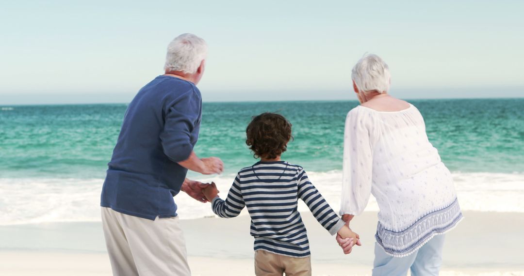 Grandparents and Child Holding Hands Enjoying Beach - Free Images, Stock Photos and Pictures on Pikwizard.com