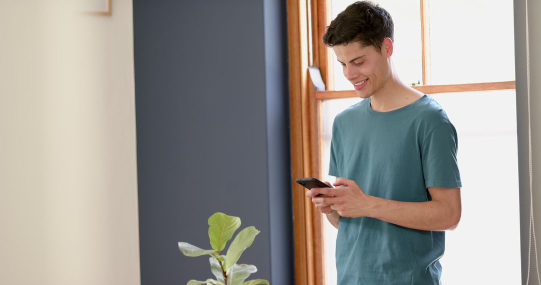 Happy Young Man Connecting with Smartphone Indoors