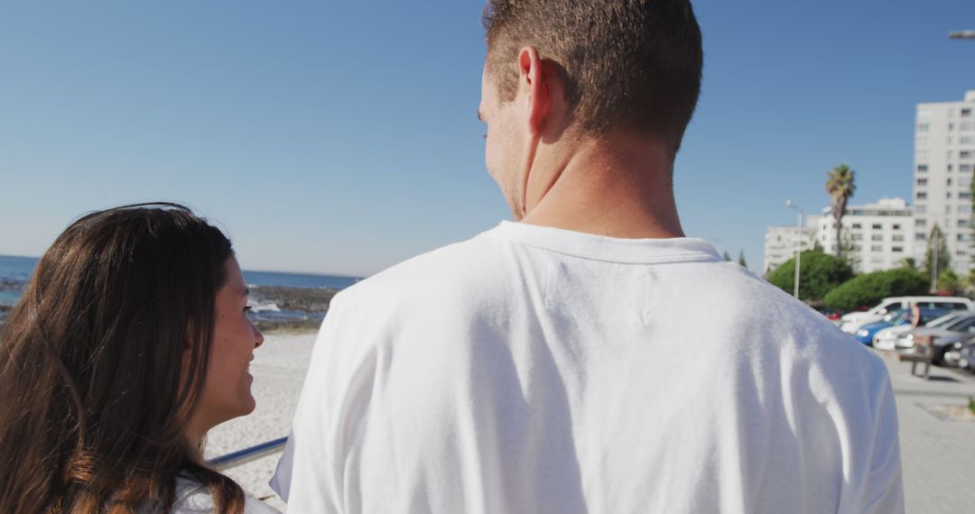 Smiling Young Couple Enjoying Beach Walk Under Clear Blue Sky - Free Images, Stock Photos and Pictures on Pikwizard.com