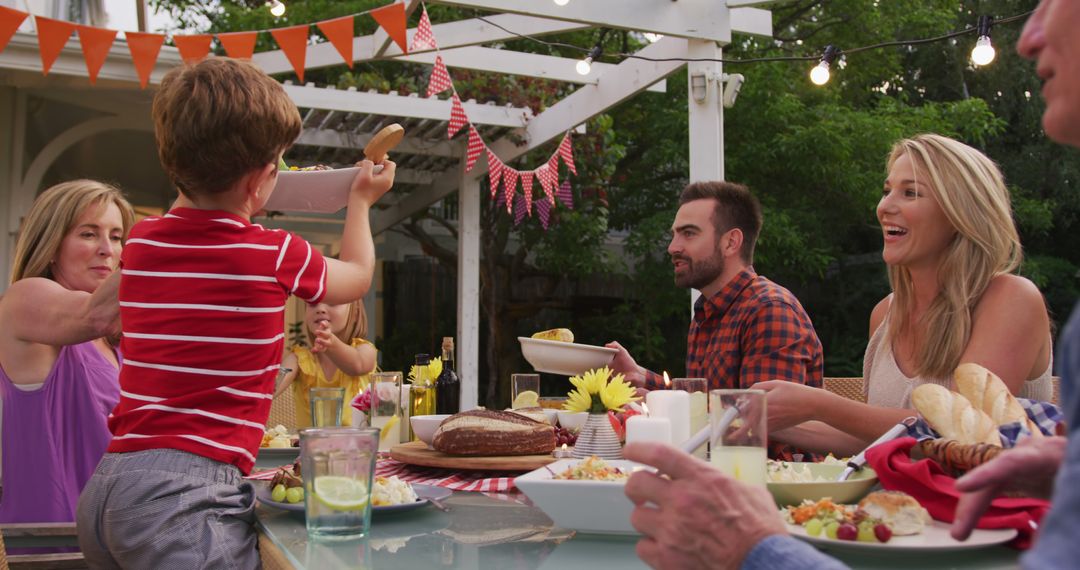 Happy Family Sharing Outdoor Meal Under String Lights in Summer Garden