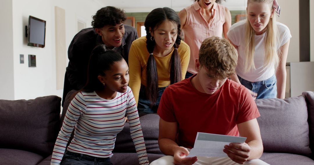 Multicultural friends gathering on sofa, reading letter and reacting to surprising news