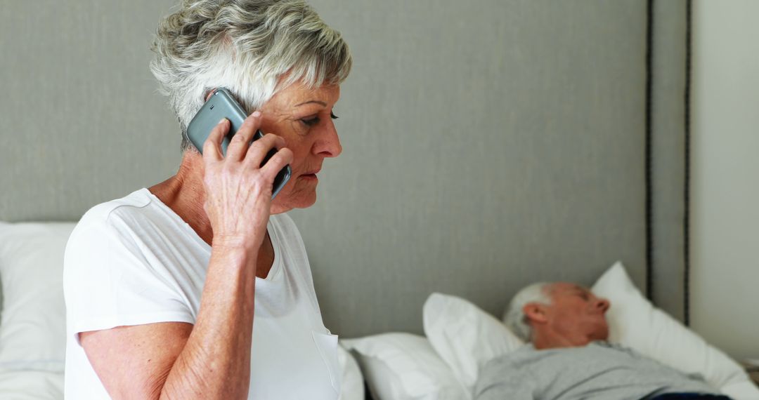 Senior Woman Taking Important Call Caring for Sleeping Partner - Free Images, Stock Photos and Pictures on Pikwizard.com