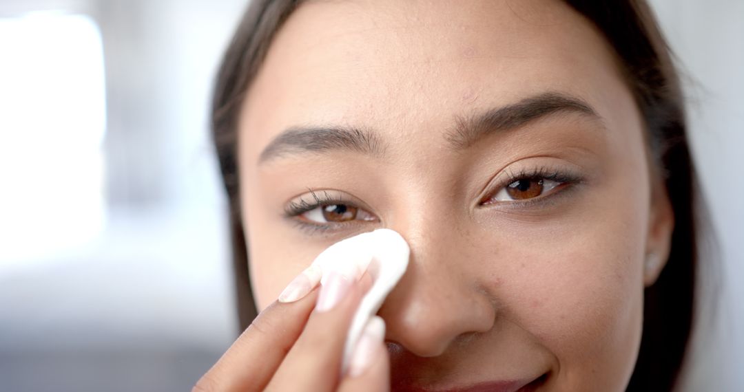 Smiling Woman Cleansing Face with Cotton Pad for Skincare Routine