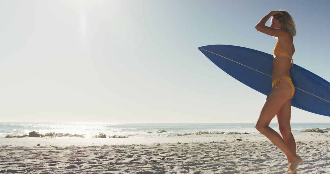 Blonde Woman in Bikini Holding Surfboard on Sunny Beach - Free Images, Stock Photos and Pictures on Pikwizard.com