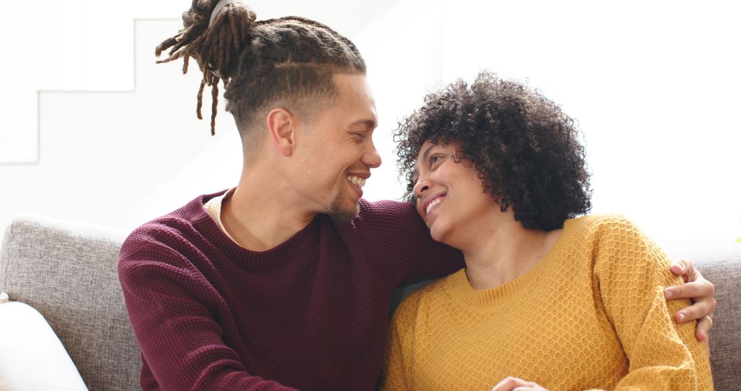 Couple sharing affectionate moment on couch at home, cozy sweaters and bright natural light