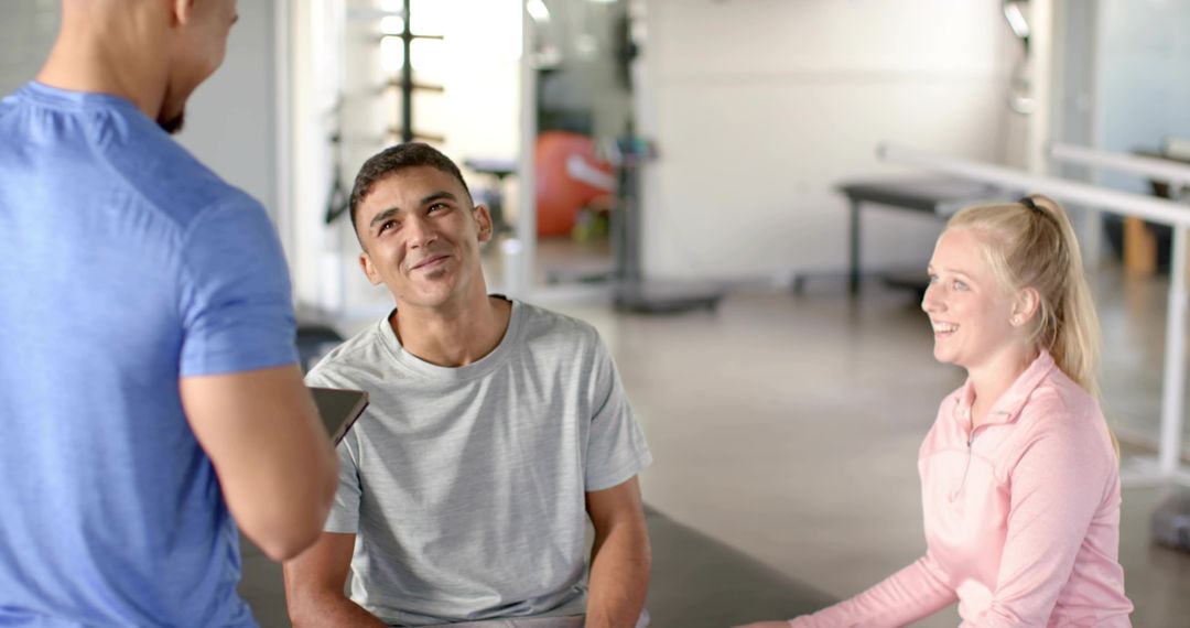 Young Athlete Listening to Trainer with Tablet during Friendly Gym Coaching Session