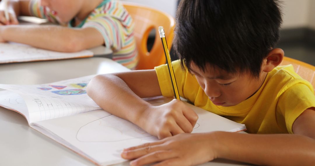 Young Boy Concentrating on Drawing in Classroom - Free Images, Stock Photos and Pictures on Pikwizard.com