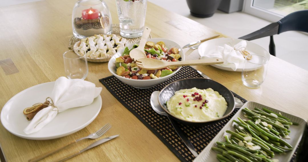 Sunlit modern dining table serving salad, creamy mashed potatoes, green beans and pastries